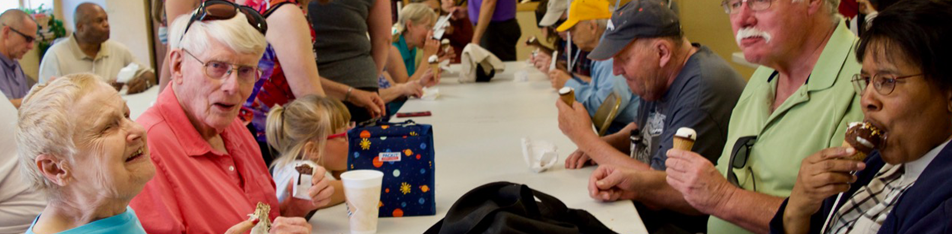 A group of blind and sighted seniors enjoy ice cream together at a gathering.