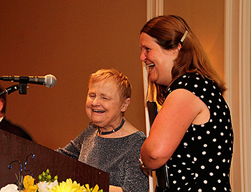 Photo of CCB founder, Diane McGeorge, speaking at podium with current director, Julie Deden, standing next to her.